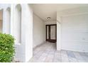 Front entrance with textured stucco, neutral colored tile, and a dark wood door offering both style and convenience at 273 Madeira Cir, Tierra Verde, FL 33715