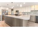 Modern kitchen with a mosaic backsplash, wine cooler, large island, stainless appliances, and pendant lighting at 736 Island Way # 606, Clearwater Beach, FL 33767