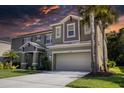 Two-story house with a green exterior, three-car garage, and landscaping at 26888 Fiddlewood Loop, Wesley Chapel, FL 33544