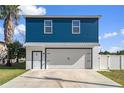 Two-story home with a blue exterior, white garage, and a landscaped yard at 3276 Sea Grape Dr, Hernando Beach, FL 34607