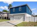 Two-story home with a blue exterior, white garage, and a landscaped yard at 3276 Sea Grape Dr, Hernando Beach, FL 34607