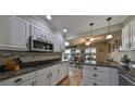 Bright kitchen featuring white cabinets, granite countertops, a mosaic backsplash, and stainless steel appliances at 407 Blackhawk Cir, Sun City Center, FL 33573