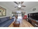 Spacious living room with an open floor plan, wood flooring, large ceiling fan, and access to outdoor spaces at 407 Blackhawk Cir, Sun City Center, FL 33573
