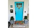 Inviting front entrance with a bright turquoise door, a charming welcome mat, and elegant planters in a cozy setting at 5946 Bayou Grande Ne Blvd, St Petersburg, FL 33703