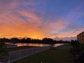 Scenic backyard view with a colorful sunset over the tranquil canal, creating a peaceful ambiance at 1074 Signet Dr, Apollo Beach, FL 33572