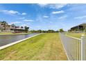 Spacious backyard with lush green grass, a white fence, and water access to a scenic canal at 1074 Signet Dr, Apollo Beach, FL 33572