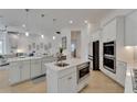 Modern, all-white kitchen featuring an island, stainless steel appliances, and an open-concept design at 1074 Signet Dr, Apollo Beach, FL 33572