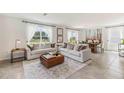 Spacious living room with light beige sofas and large windows overlooking a conservation area at 36023 Sunflower Hill Dr, Zephyrhills, FL 33541