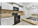 Cozy kitchen features white cabinets, black appliances, and neutral countertops and backsplash at 5606 Pinnacle Heights Cir # 304, Tampa, FL 33624