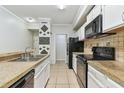 Efficient kitchen design featuring white cabinets, black appliances, and granite countertops at 5606 Pinnacle Heights Cir # 304, Tampa, FL 33624