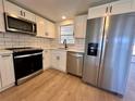 Modern kitchen featuring white cabinets, stainless steel appliances, and white subway tile backsplash at 7521 Bougenville Dr, Port Richey, FL 34668