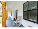 Inviting front porch with rocking chair and wooden columns at 8611 Quail Hollow Blvd, Wesley Chapel, FL 33544