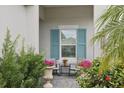 Side porch with blue shutters, rocking chairs, and flowering plants at 10025 Lake Wales Cir, Sarasota, FL 34241