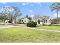 Cute cottage style home with green grass and a tree-lined street at 8130 3Rd N St, St Petersburg, FL 33702