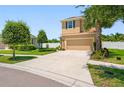 Two-story house with tan exterior, two-car garage, and landscaped yard at 8315 Round Leaf Ln, Riverview, FL 33578