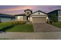 Two-story house with tan siding, stone accents, and a two-car garage at 7122 Heron Walk Ln, Wesley Chapel, FL 33545