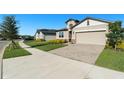 Tan house with gray roof, stone accents, and a two-car garage at 7122 Heron Walk Ln, Wesley Chapel, FL 33545