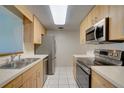 Galley kitchen with stainless steel appliances and light wood cabinets at 2621 10Th St, Englewood, FL 34224