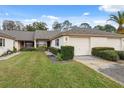 Exterior of a light-colored villa with a two-car garage and lush landscaping at 3309 Lori Ln, New Port Richey, FL 34655