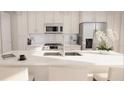Bright white kitchen featuring stainless steel appliances and a breakfast bar with modern counter stools at 600 3Rd S Ave # 405, St Petersburg, FL 33701
