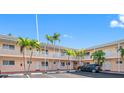 Exterior view of condo building with parking and tropical landscaping at 19417 Gulf Blvd # C-211, Indian Shores, FL 33785