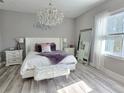 Luxurious bedroom with a white tufted headboard bed, chandelier, and wood-look floors at 122 W Sligh Ave, Tampa, FL 33604