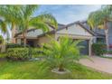 Two-story house with a dark gray garage door and palm trees at 10147 Newminster Loop, Ruskin, FL 33573