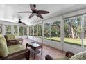 Enclosed sunroom with tile floor and walls of windows, furnished with wicker furniture, offering views of the surrounding greenery at 3203 Audubon Ct, Tarpon Springs, FL 34688