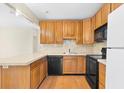 View of the kitchen, featuring wood cabinets, black appliances, and tile backsplash at 6415 Sandpiper S Way, St Petersburg, FL 33707