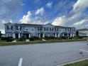 Long shot of townhomes with blue siding, black shutters, and trimmed front yard at 2409 Hearth Dr, Odessa, FL 33556