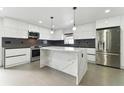 Modern kitchen boasts white cabinets, marble island, and stainless steel appliances at 26728 Hickory Loop, Lutz, FL 33559