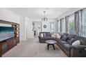 Bright living room featuring a large grey sectional sofa, carpeted floors, and ample natural light at 4735 Rolling Green Dr, Wesley Chapel, FL 33543