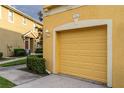 Close-up of a yellow townhome's garage with landscaping and walkway at 9042 Moonlit Meadows Loop, Riverview, FL 33578