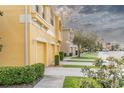 Row of townhouses with yellow exteriors, garages, and lush landscaping at 9042 Moonlit Meadows Loop, Riverview, FL 33578