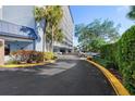 An exterior shot of a blue and white condo building with palm trees and a yellow-lined road leading to the entrance at 4939 Floramar Ter # 501, New Port Richey, FL 34652