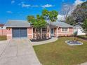 Pink house with mature landscaping and a two-car garage at 6955 Sandalwood Dr, Port Richey, FL 34668