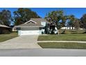 Charming light green house with a white garage door and manicured lawn at 1005 Lake Avoca Pl, Tarpon Springs, FL 34689