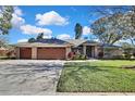 Brick home with three-car garage and a manicured lawn at 19505 Coachlight Way, Lutz, FL 33549