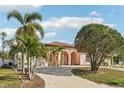 Well-maintained light pink house with palm trees, a circular driveway, and arched entryway at 5269 61St N Way, Kenneth City, FL 33709