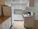 Well-lit kitchen featuring white appliances, white cabinets, and matching countertops at 6177 Chesham Dr # 6, New Port Richey, FL 34653
