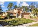 Inviting single-Gathering home features a well-kept lawn, arched entryway with stately columns, a paver driveway, and a two-car garage at 4275 Caskie Pl, Brooksville, FL 34604