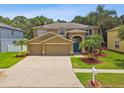 Inviting home featuring a spacious driveway, three-car garage, landscaped yard, and a blue front door at 15815 Muirfield Dr, Odessa, FL 33556