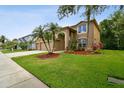 Beautiful two-story home with a large, green lawn, palm trees, and a well-maintained landscape at 15815 Muirfield Dr, Odessa, FL 33556