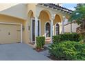 A charming front porch featuring a dark wooden door, decorative columns, and manicured shrubbery alongside the driveway at 20314 Chestnut Grove Dr, Tampa, FL 33647