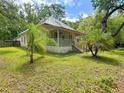 Charming home featuring a welcoming porch, set amidst a lush, green lawn and mature trees at 262 Pryor St, Brooksville, FL 34601
