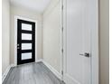 A clean, modern entryway featuring a black door with glass panels and gray tile flooring at 2246 Fiesta Dr, Sarasota, FL 34231