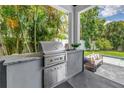Outdoor kitchen featuring stainless steel grill and lush, tropical landscaping at 2246 Fiesta Dr, Sarasota, FL 34231