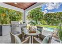 Covered outdoor dining area with a built-in grill overlooking the inviting pool at 2246 Fiesta Dr, Sarasota, FL 34231