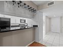 Stylish kitchen featuring white cabinets, black countertops, and modern appliances at 1033 Bowsprit Ln # 1406, Holiday, FL 34691