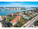 Stunning aerial view of waterfront condos with a serene bay and cityscape backdrop, lush landscaping, and ample parking at 8711 Blind Pass Rd # 307A, St Pete Beach, FL 33706